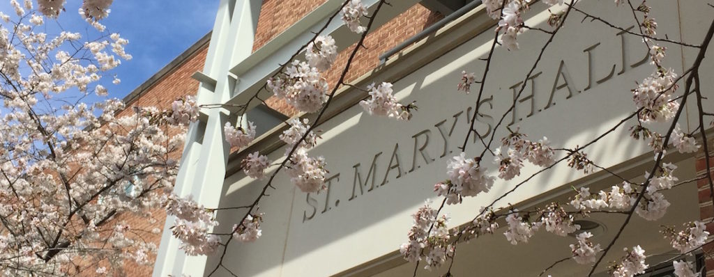 The exterior of St. Mary's Hall with pink blossoms in front of the building