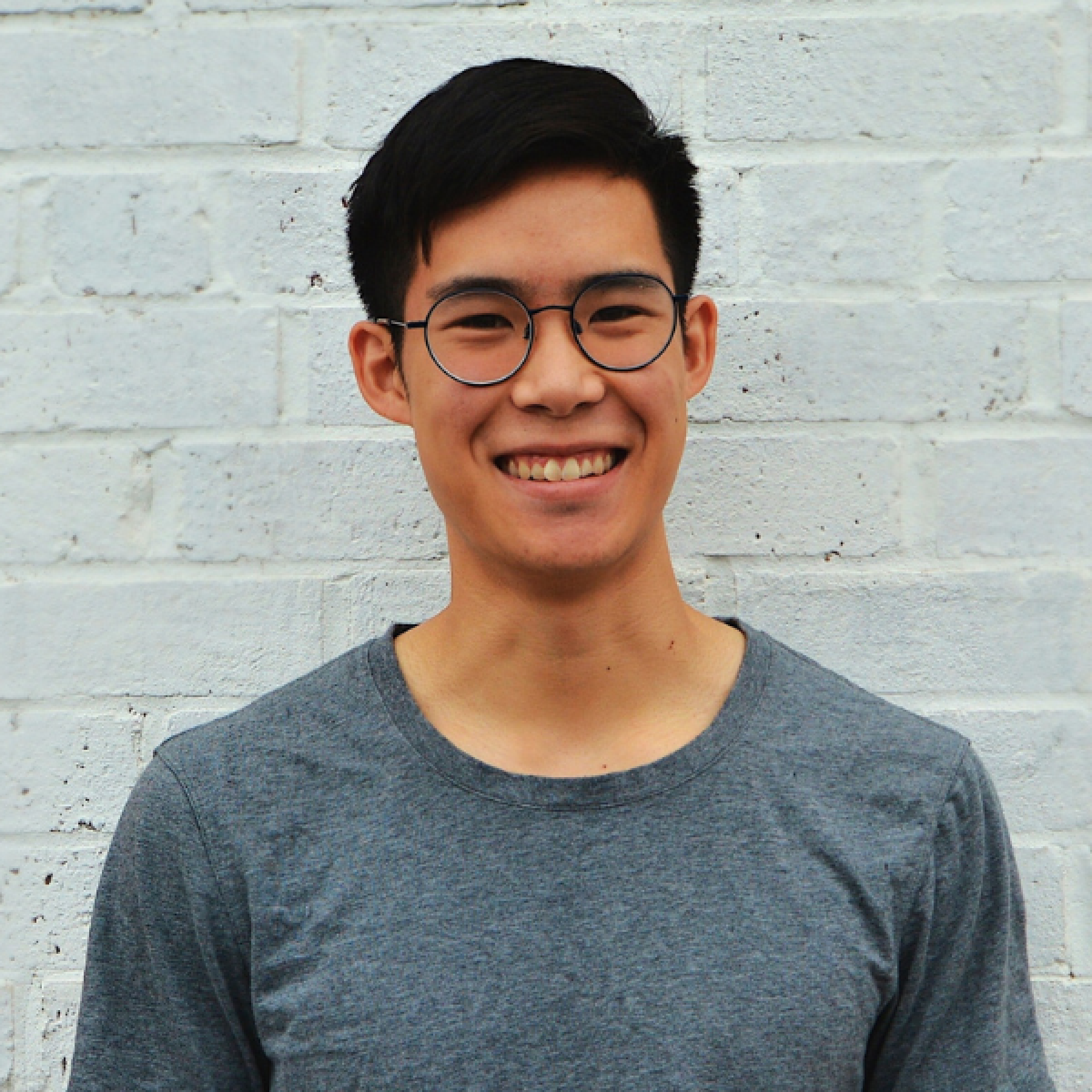 An image of Phil Wong, an alumnus and creator of a food startup, wearing a gray T-shirt and glasses.