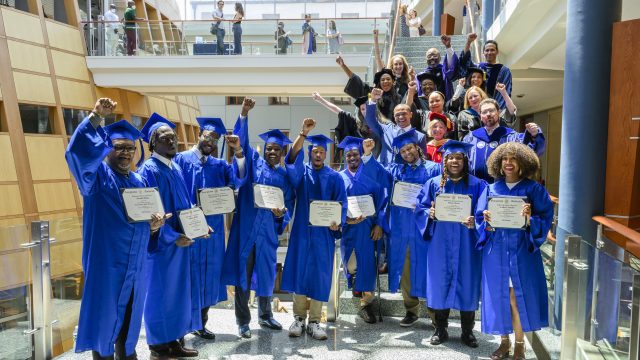 An image of graduates from the Pivot Program wearing blue cap and gowns.