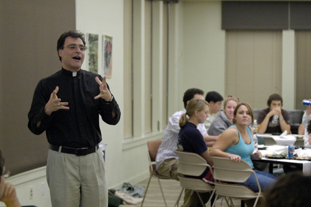 A man with a collar teaches in a classroom of teenaged students