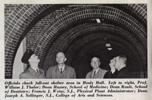 A newspaper clipping of four people standing in Healy basement under the archway in the 1950s.