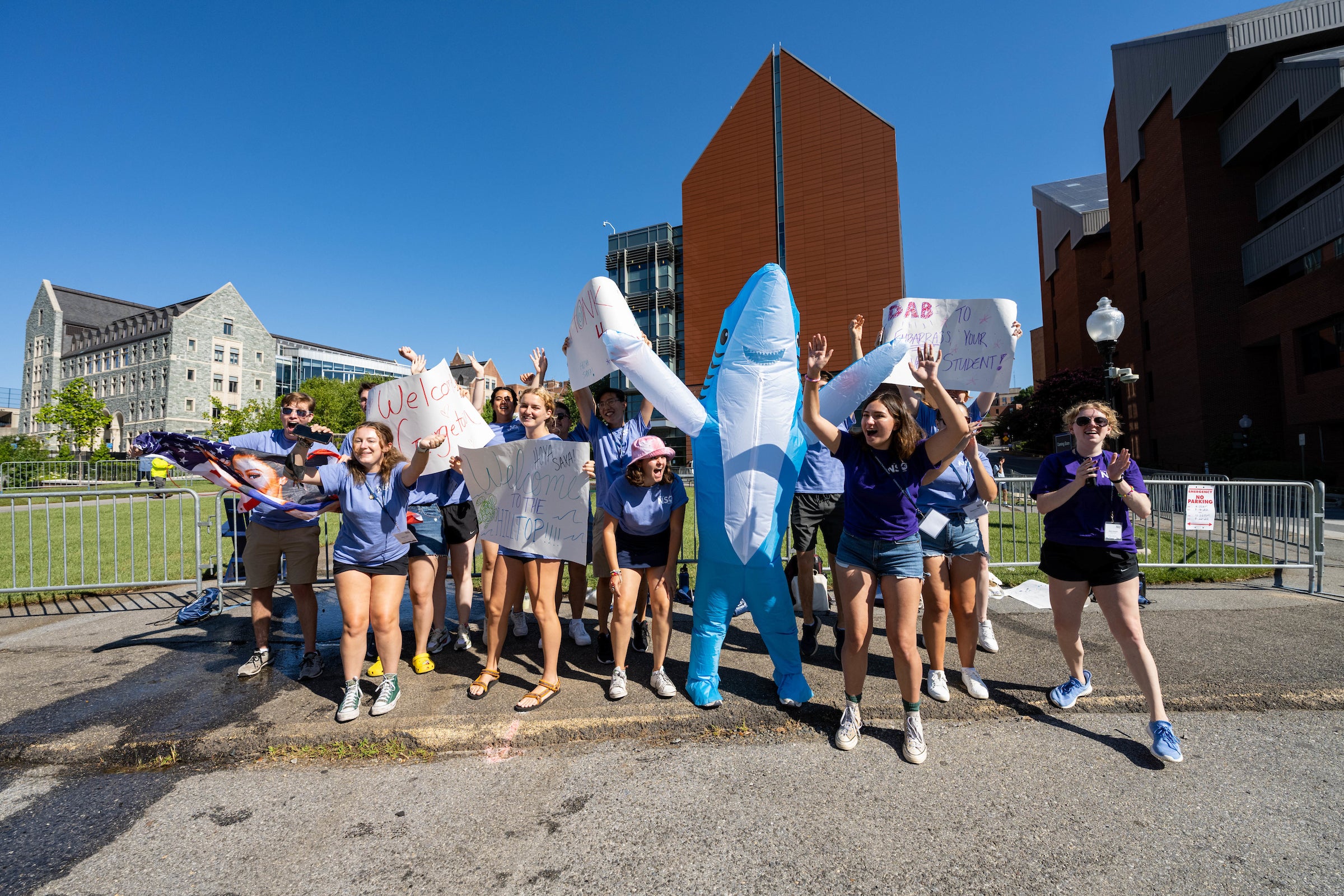 Students in matching T-shirts and one dressed as a shark hold signs and cheer