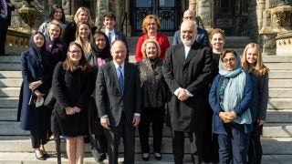 President DeGioia stands with a group of dignitaries in front of Healy Hall