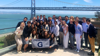 Students hold a Georgetown G sign in front of a bridge
