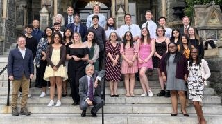 A group of college students pose for a picture on the front steps of Healy Hall during their weeklong predoctoral summer institute at Georgetown.