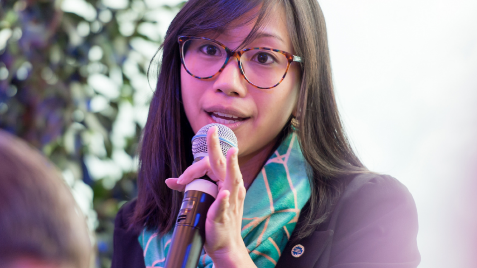 An image of Tiffany Yu (B'10) speaking into a microphone at an event.
