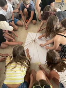 A group of Ukrainian teenagers sit in a circle and pull strings on a piece of paper as part of a peace-building exercise at a summer camp in Montenegro.