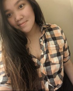 Young woman with long hair wears a plaid button down shirt in a selfie