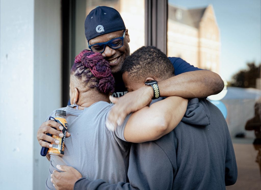 Briana Green and her husband John Green hug their son, Keiran Green, outside his residence hall on move-in day in August 2022.
