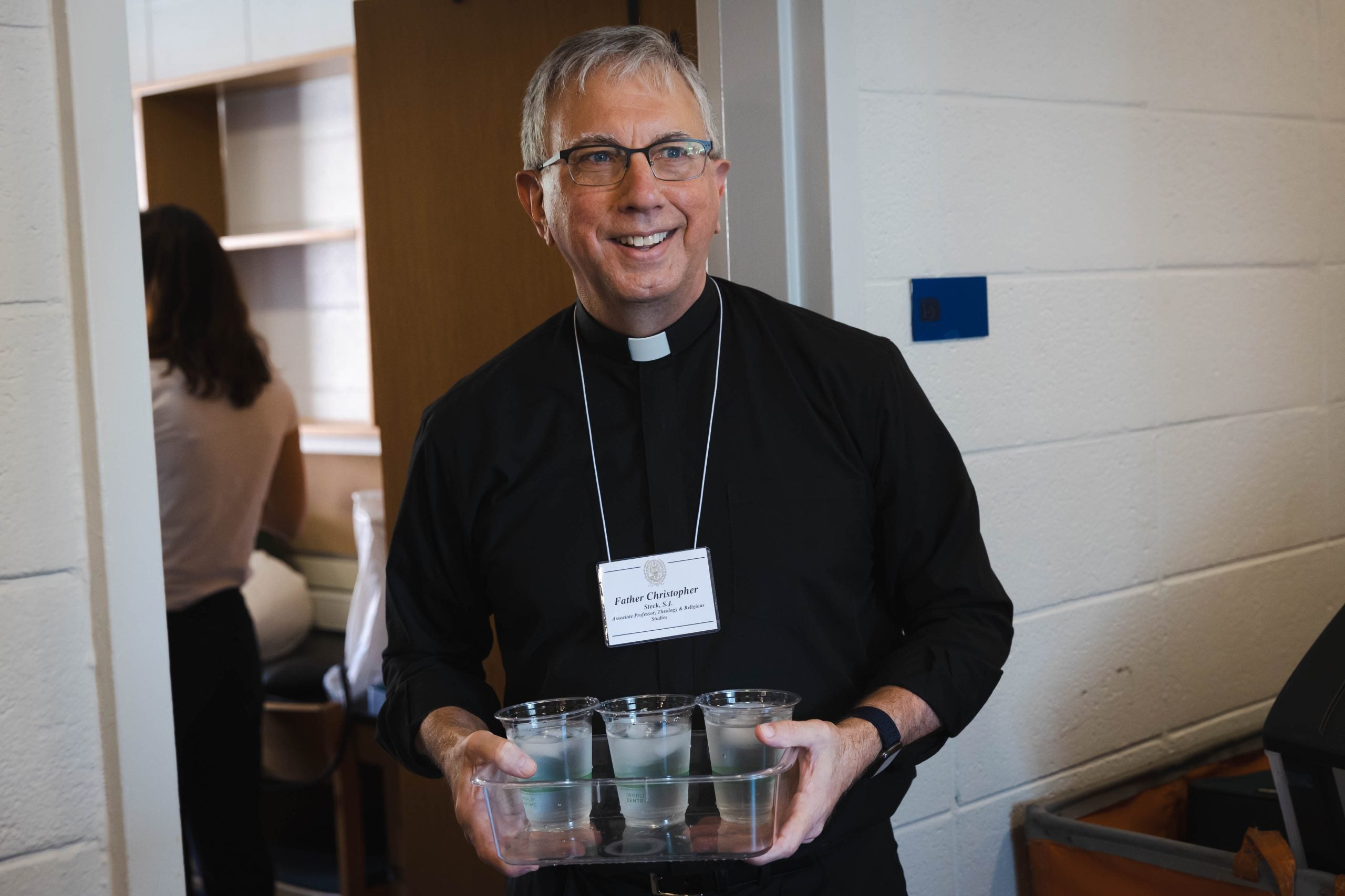 Fr. Steck, SJ, a chaplain in New South Hall, carries a tray of ice waters to new first years who are moving into the residence hall.