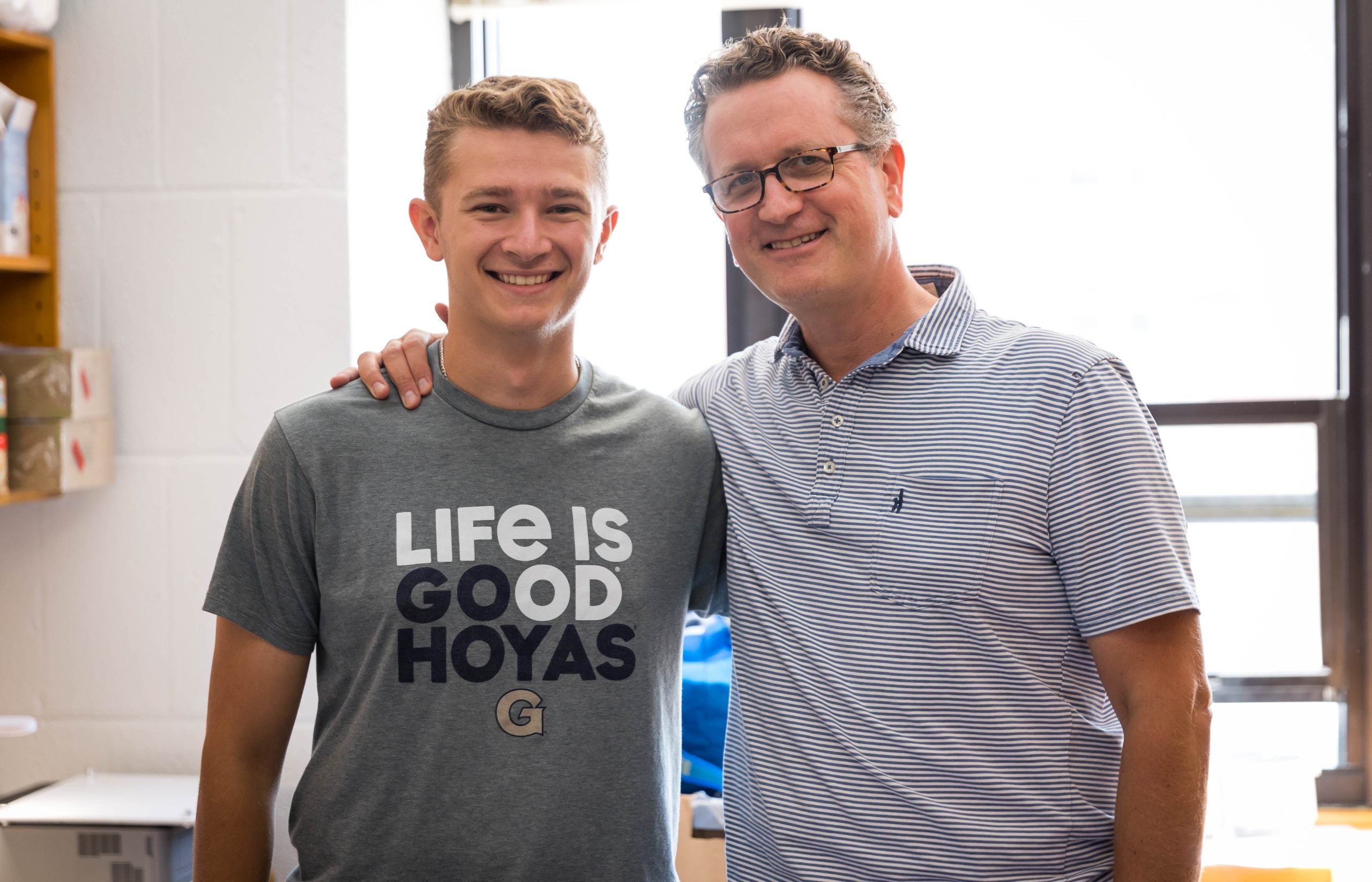 John Breitfelder stands with his arm around his dad, Matthew Breitfelder, in his dorm on Georgetown's campus. 