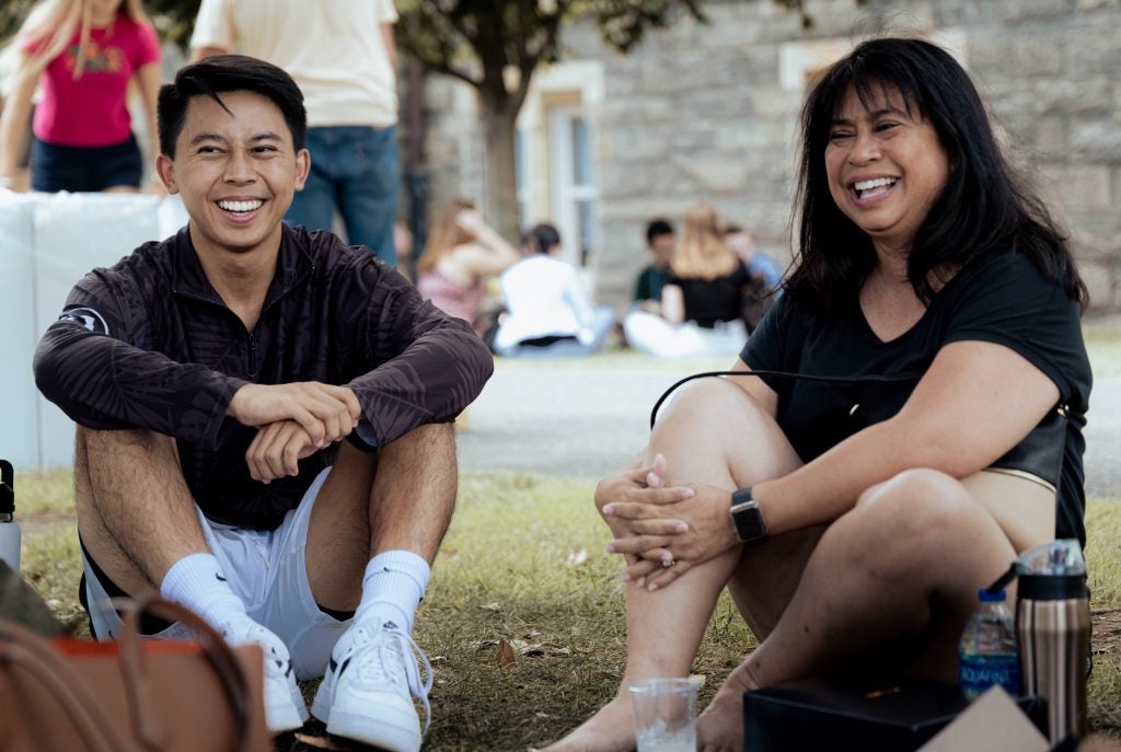 Wyatt Nako (C'26) sits with his mother, Judy Nako, on the lawn outside Healy Hall during move-in 2022.
