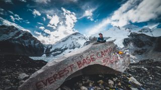 An image of Sarah Watson sitting on top of a rock with mountains in the background at Mt. Everest base camp in Nepal.