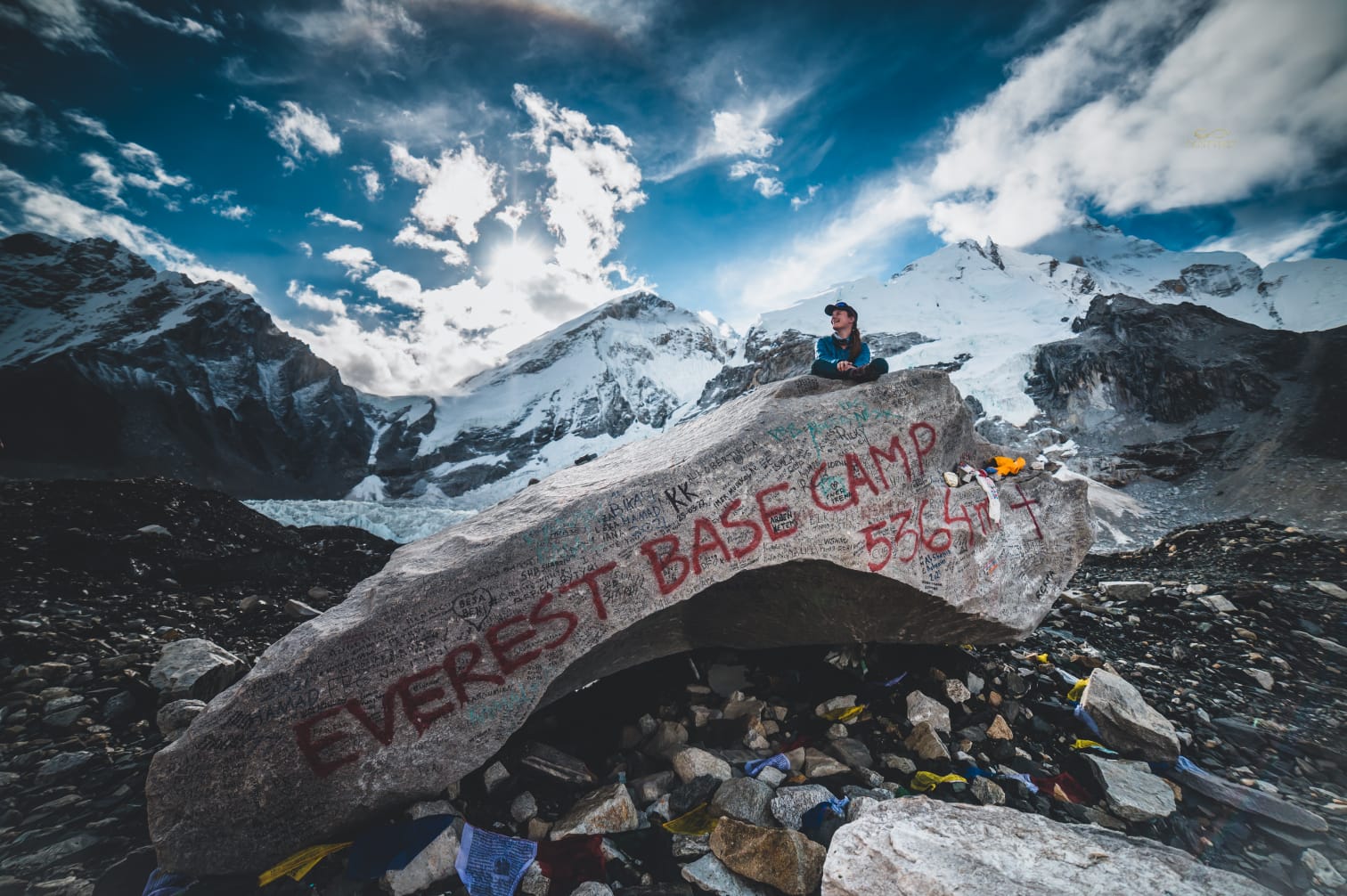 An image of Sarah Watson sitting on top of a rock with mountains in the background at Mt. Everest base camp in Nepal.
