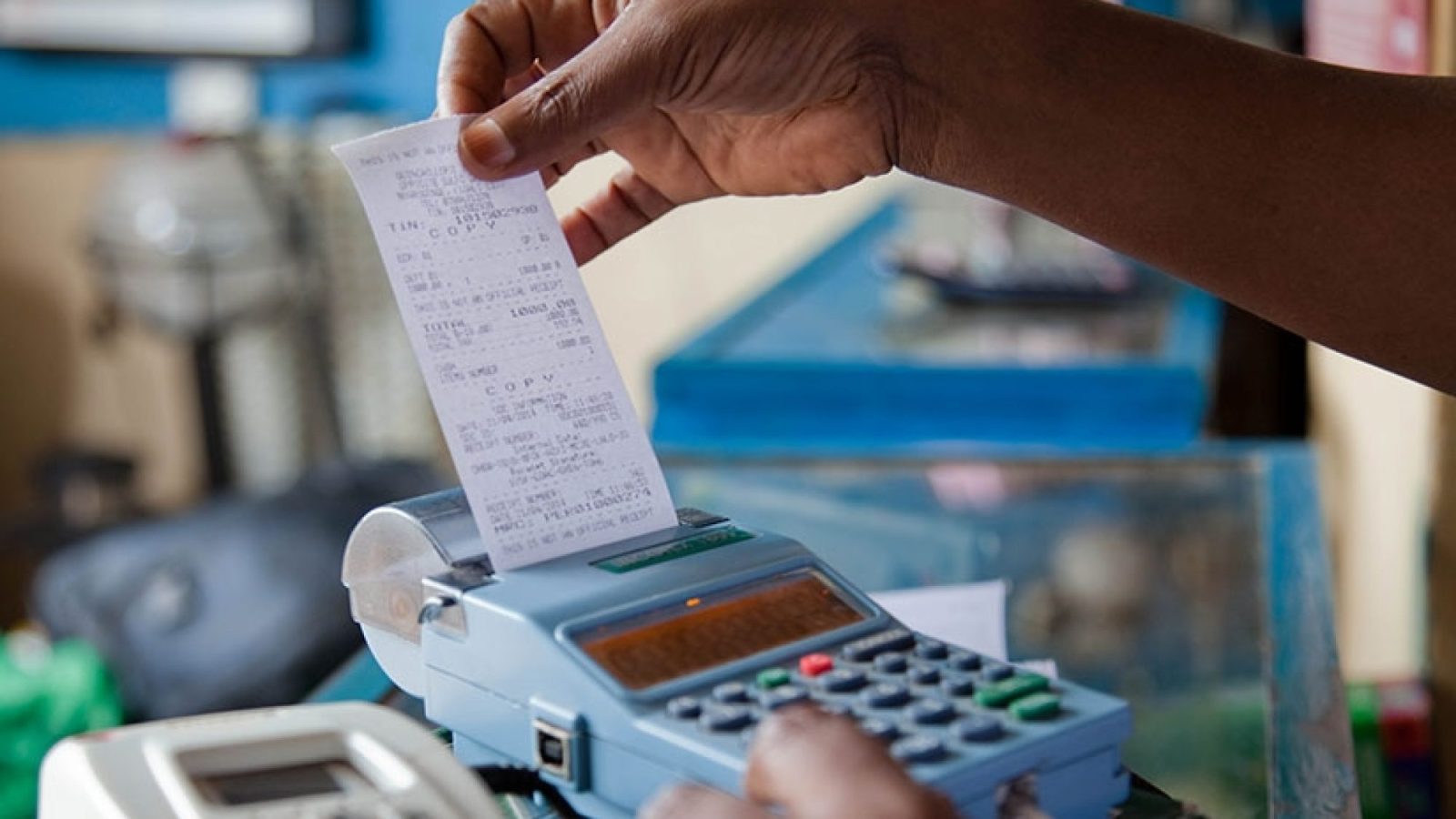 An image of a hand holding a receipt rolling out of an electronic cash register.
