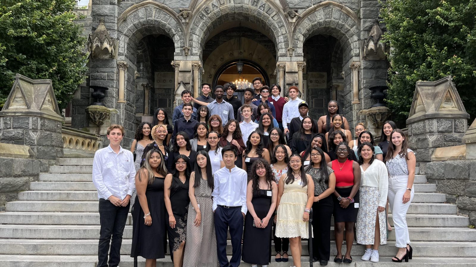 A group of high school students pose together on the steps of Healy Hall during their three-week summer college prep immersion.