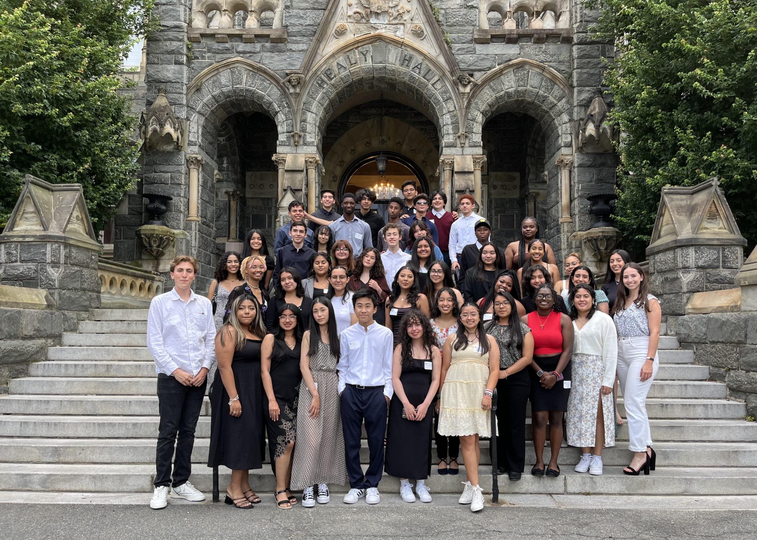 A group of high school students pose together on the steps of Healy Hall during their three-week summer college prep immersion.
