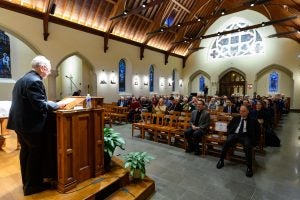 Fr. O'Malley speaks to an audience from a podium on the alter of Dahlgren Chapel