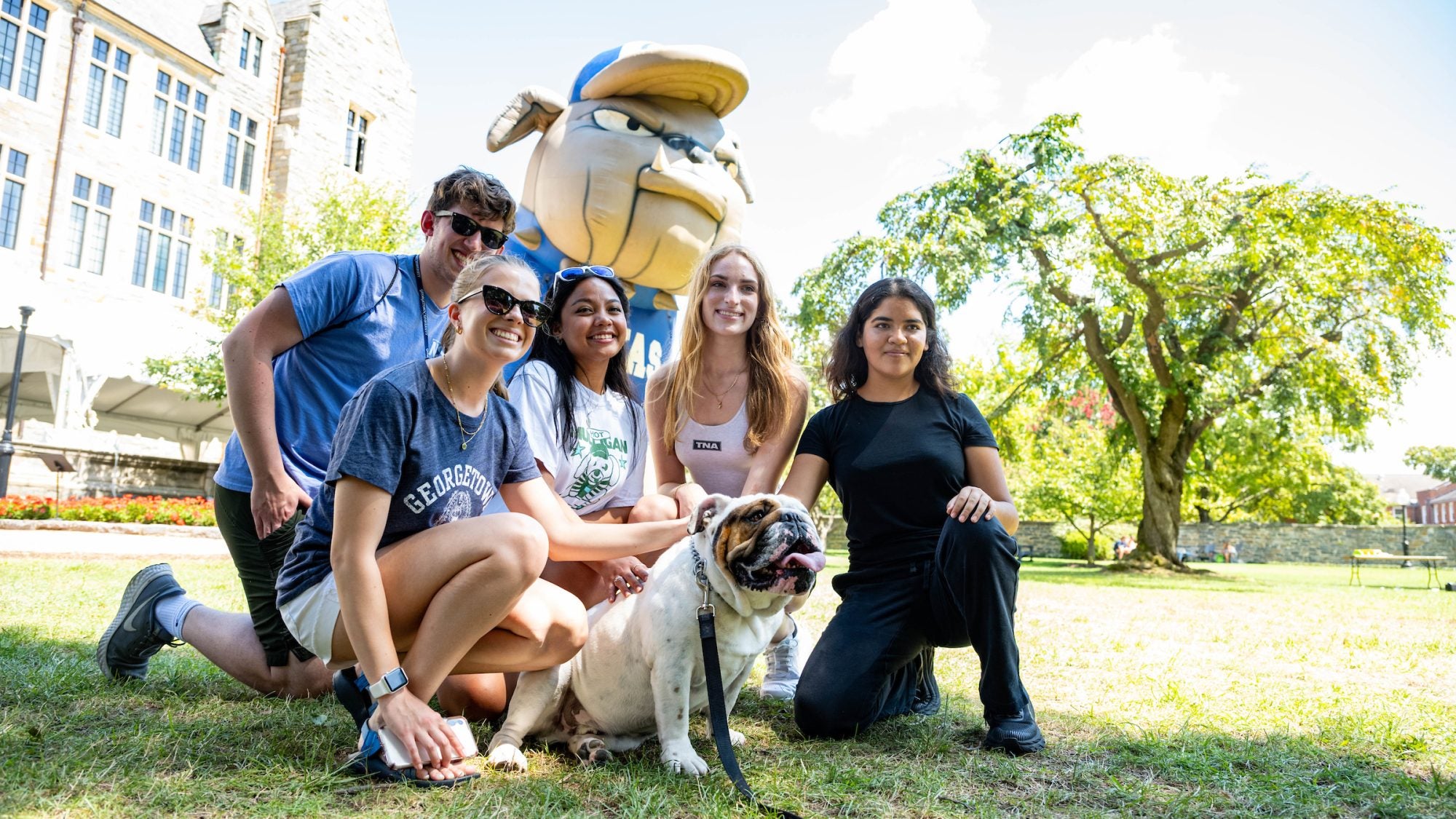 Students kneel in front of a blow-up Jack the Bulldog with the real Jack the Bulldog