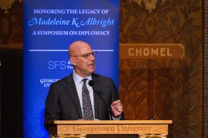 Dean Joel Hellman speaks from behind a podium on Gaston Hall stage