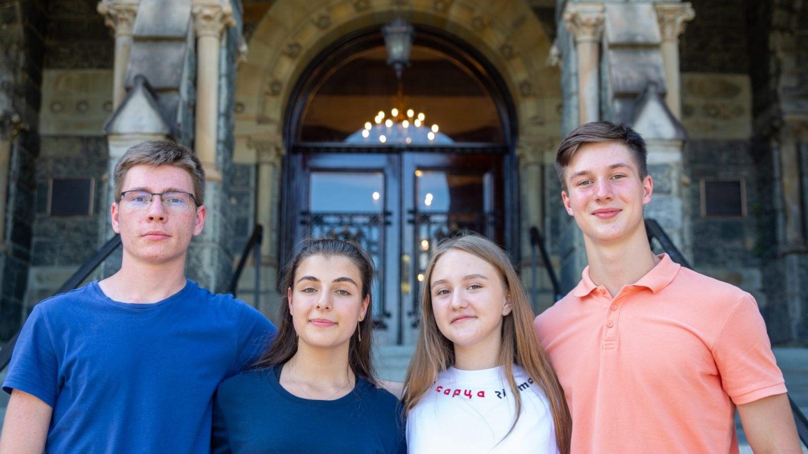 Four students in Georgetown&#039;s new scholarship for students impacted by the war in Ukraine pose outside Georgetown&#039;s Healy Hall on its main campus.