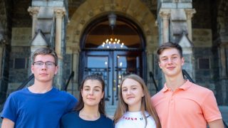 Four students in Georgetown&#039;s new scholarship for students impacted by the war in Ukraine pose outside Georgetown&#039;s Healy Hall on its main campus.