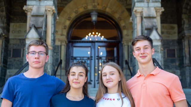 Four students in Georgetown's new scholarship for students impacted by the war in Ukraine pose outside Georgetown's Healy Hall on its main campus.