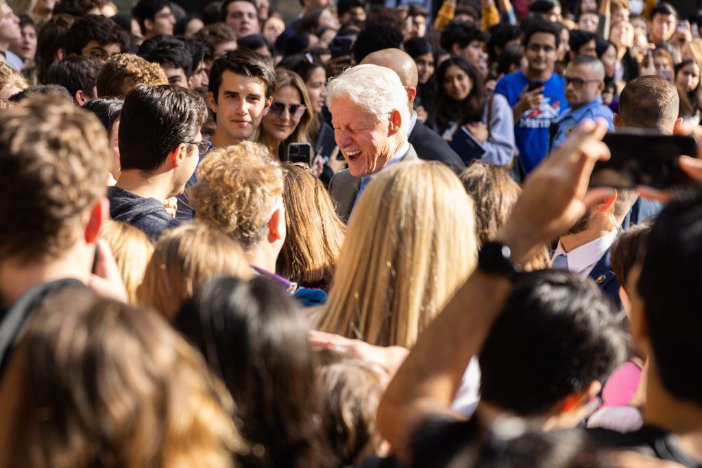 President Bill Clinton closes his eyes and smiles while in a large crowd of students
