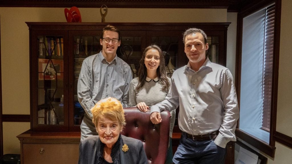 Students stand behind Madeleine Albright in her office.