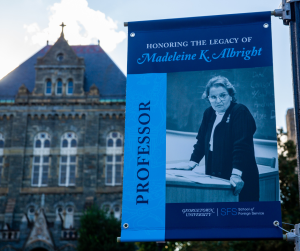 Banner hanging from a lamp post in front of Healy Hall with a photo of Alright and the text "Professor" along the left side