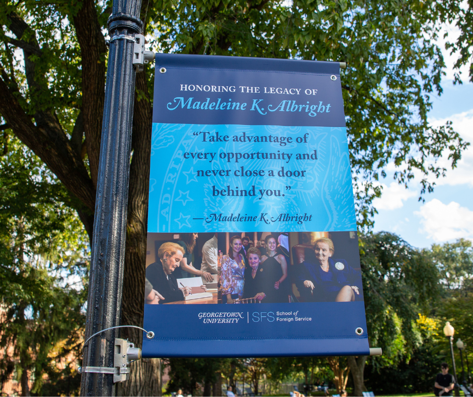 Banner hanging from a lamp post with photos of Albright and her quote "Take advantage of every opportunity and never close the door behind you."