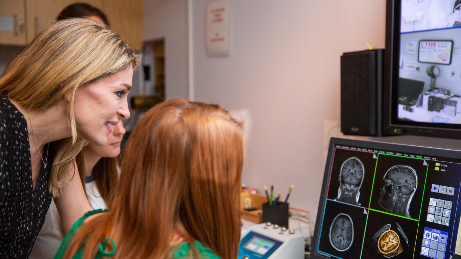 Professor Abigail Marsh (far left) looks over MRI scans with a student (right) in her lab.