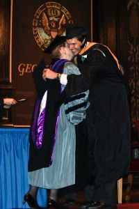 Madeleine Albright (left) congratulates David Trichler (right) as he walks across the stage of Gaston Hall on his graduation day.