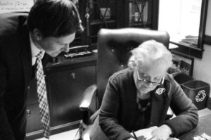 David Trichler (left) stands next to Madeleine Albright's desk as she writes.