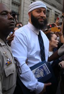 Adnan Syed holds a Georgetown book while being released from prison wearing a collared white shirt and black tie