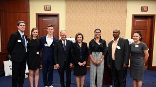 Georgetown students stand with Nancy Pelosi and Georgetown President John J. DeGioia