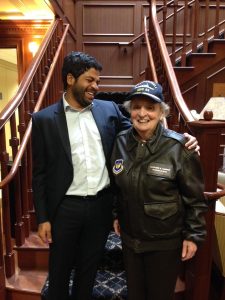 Shyam Sundaram (left) poses with Madeleine Albright (right), who's wearing a hat and a bomber jacket.