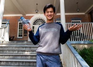 Young man wearing a blue and gray Georgetown sweatshirt holds a water bottle