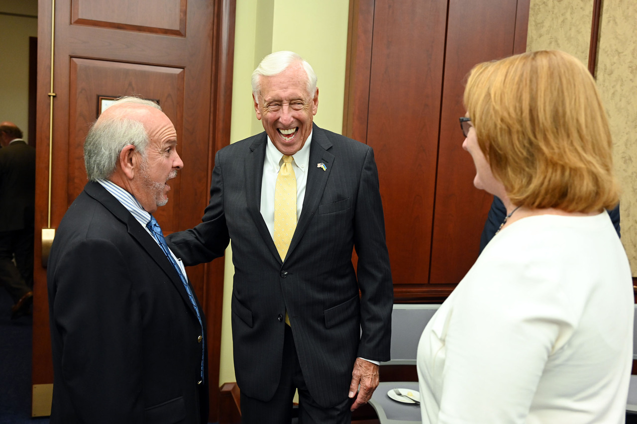 Rep. Steny Hoyer wears a suit and yellow tie and laughs with two others