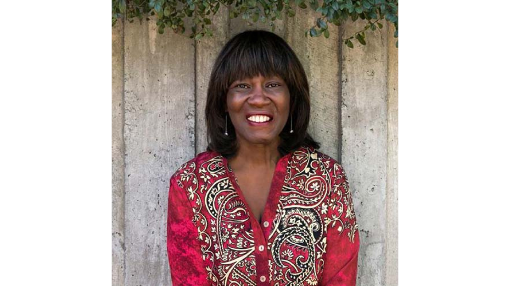 Patricia Smith, smiling, photographed against wooden backdrop.