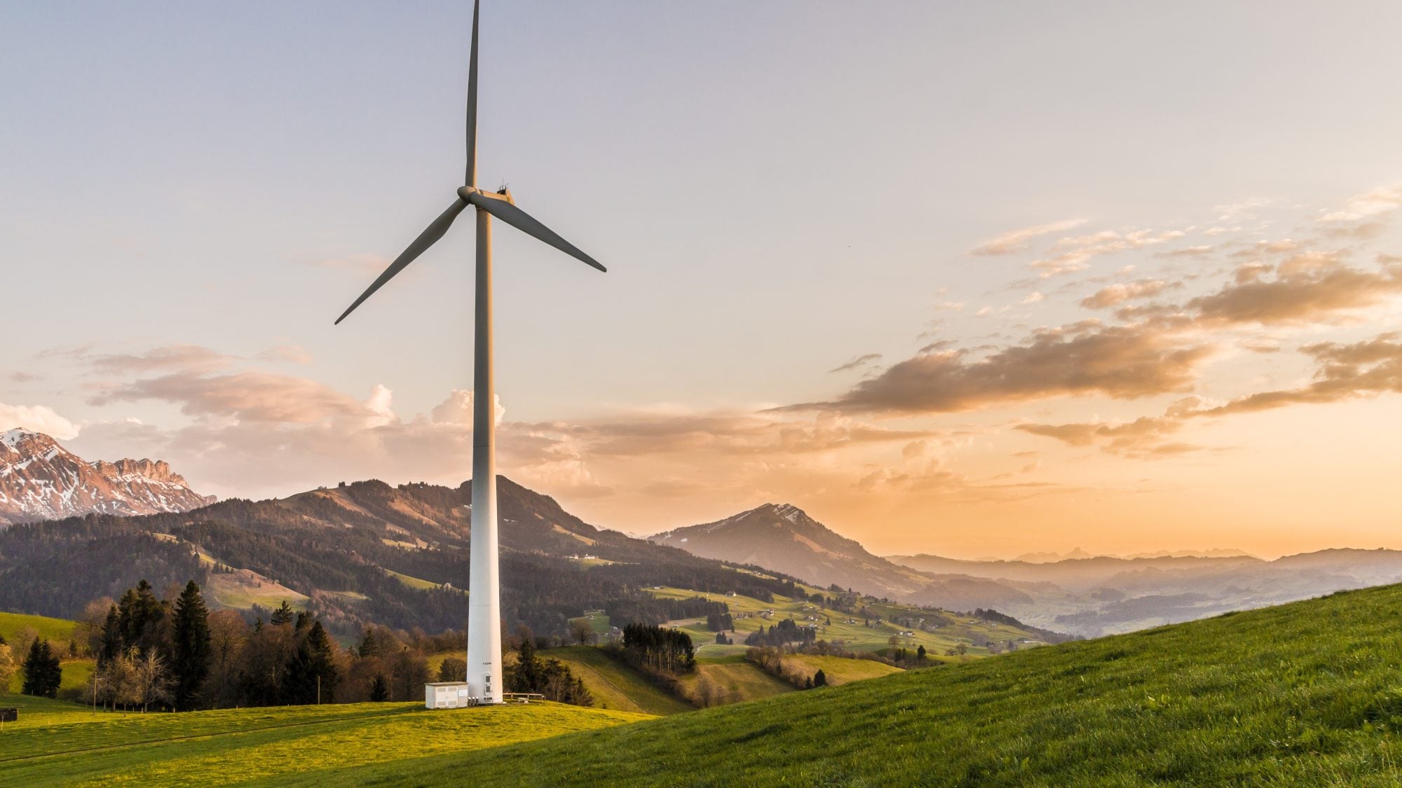 Wind turbine on grassy, mountainous landscape.