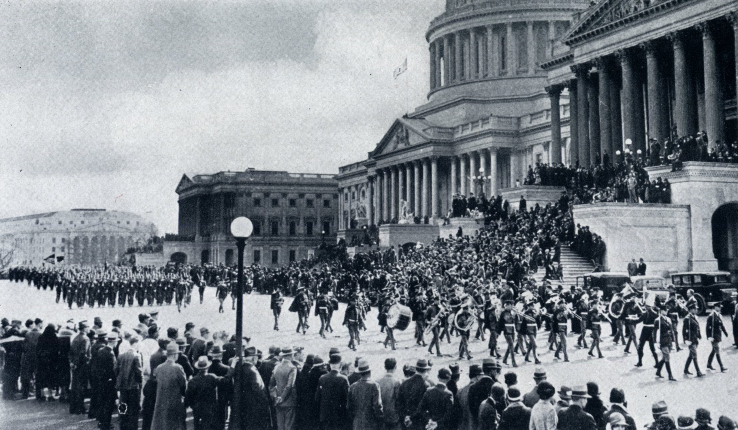 A black-and-white photo from Georgetown's 1933 yearbook shows the Georgetown band marching in downtown Washington, DC, in the Army Day parade