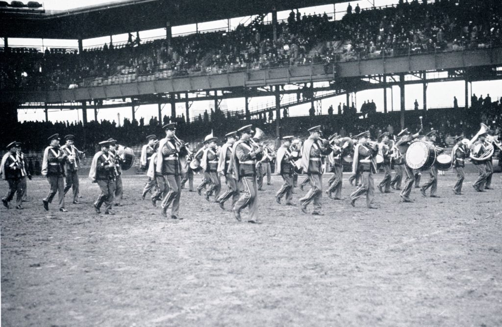 The Pep Band marches across a baseball stadium in 1936