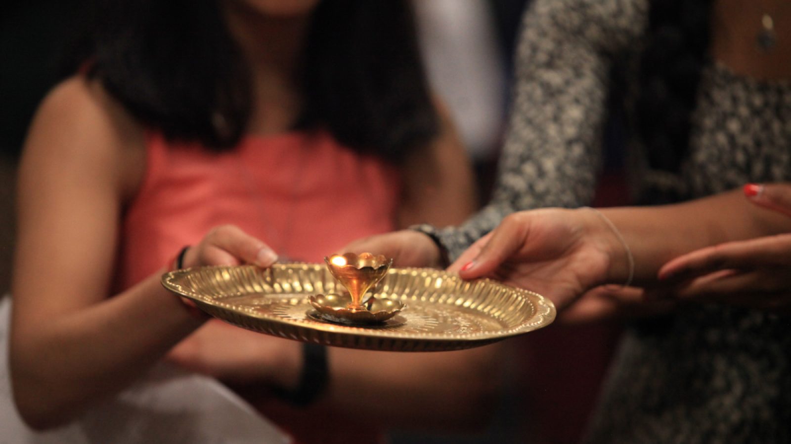 Students hold a gold ghee-lamp in the Hindu ritual of aarti, which asks God to bless the devotee&#039;s heart and mind with love and compassion.