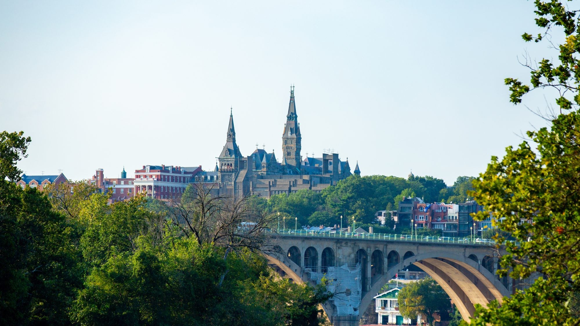 Skyline of Georgetown&#039;s campus and Healy Hall towers behind Key Bridge at sunset