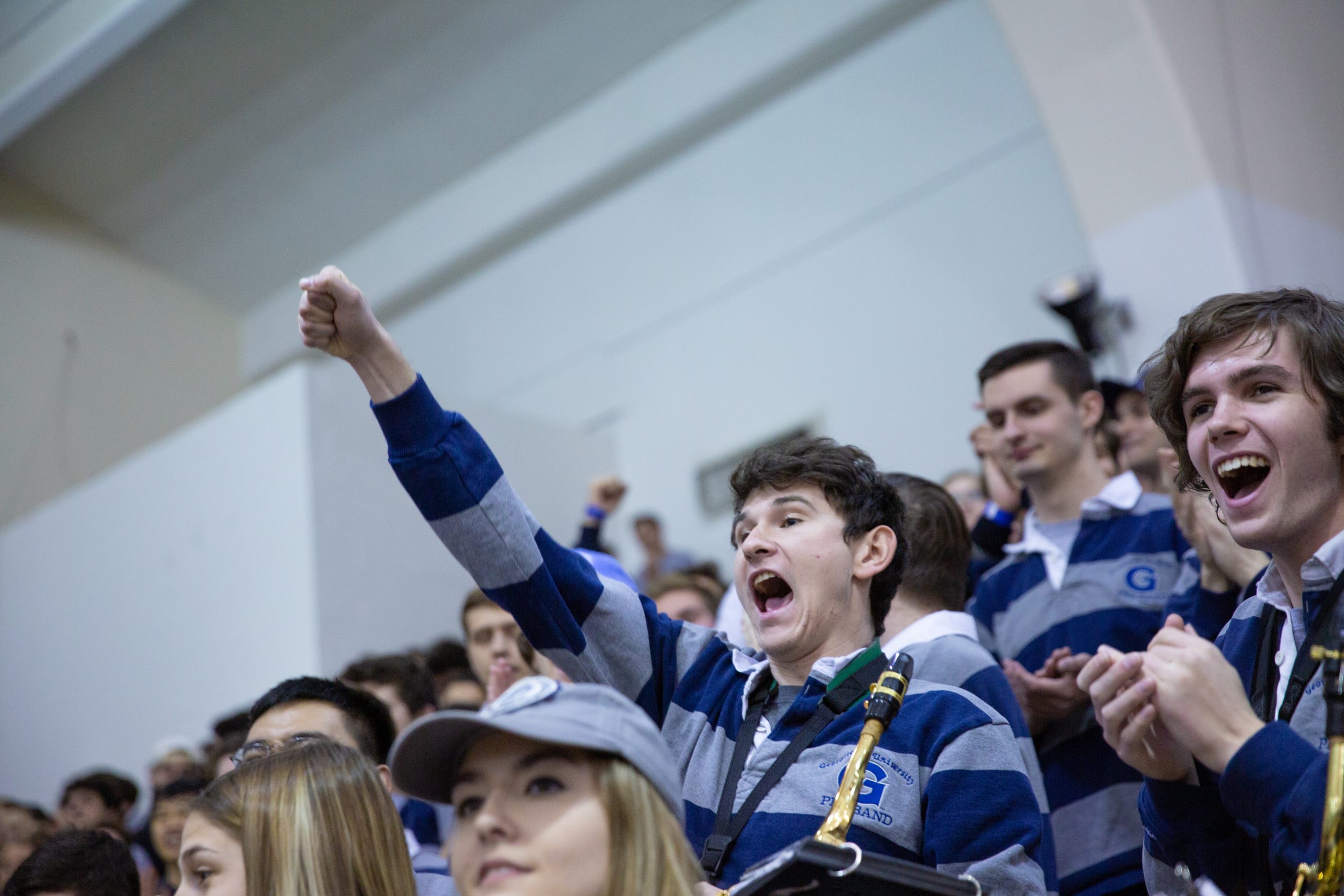 A member of the Pep Band shouts and raises his arm out to cheer on Georgetown's basketball team at a 2019 game.
