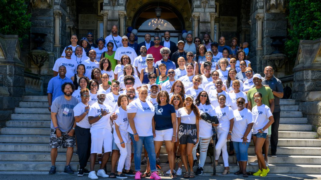 Members of the organizes the Soul Hoyas pose for a picture on the steps of Healy Hall during their annual reunion event. Many of the group members wear white T-shirts that say, 
