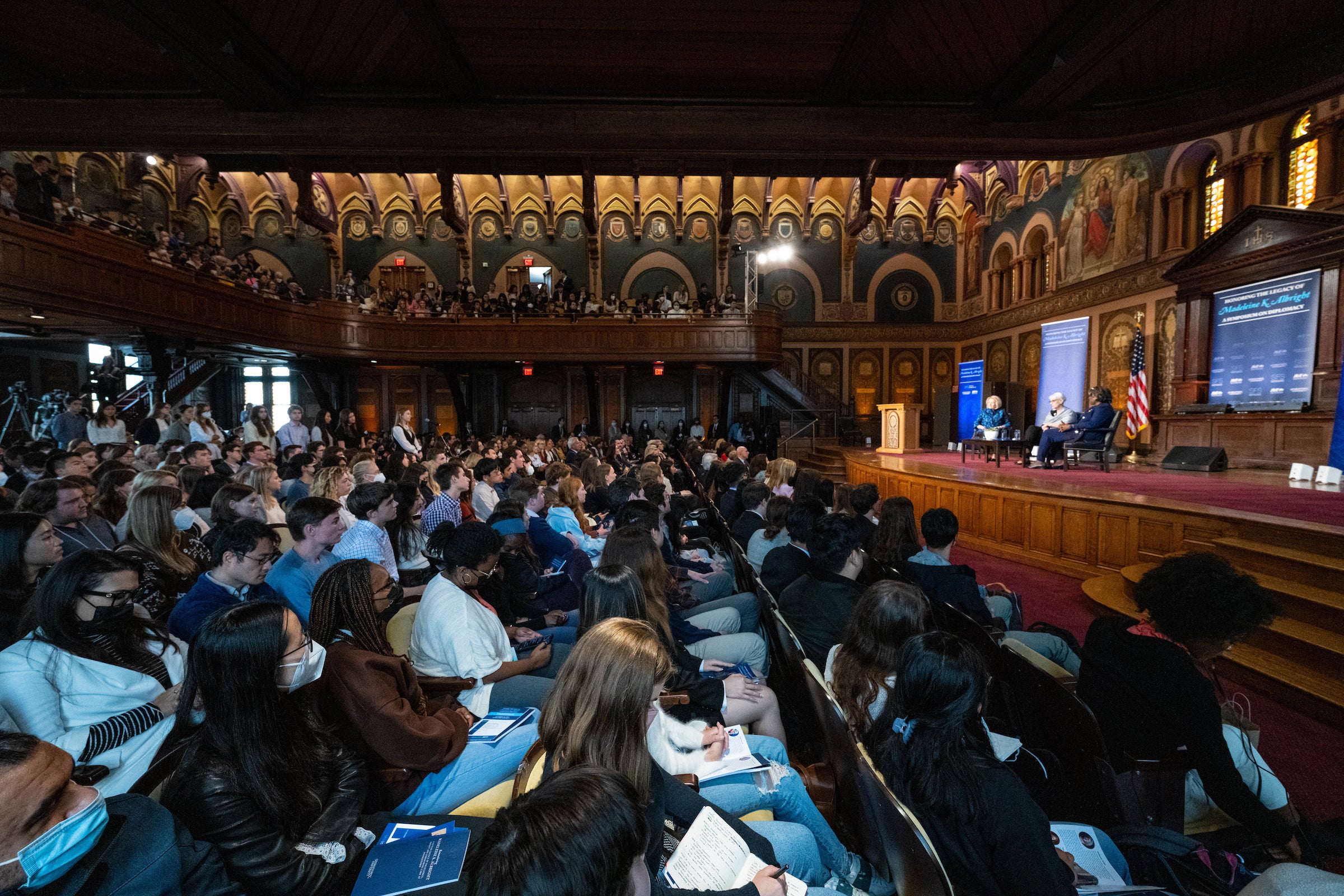 crowd of students in two levels of seats looking at speakers on the stage