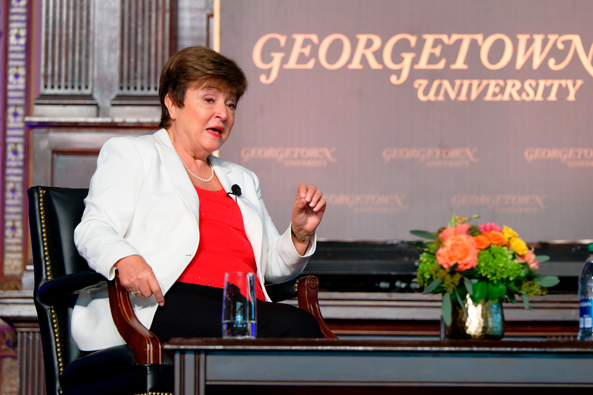 Kristalina Georgieva wears a red blouse and white blazer while sitting in front of a sign that says Georgetown University