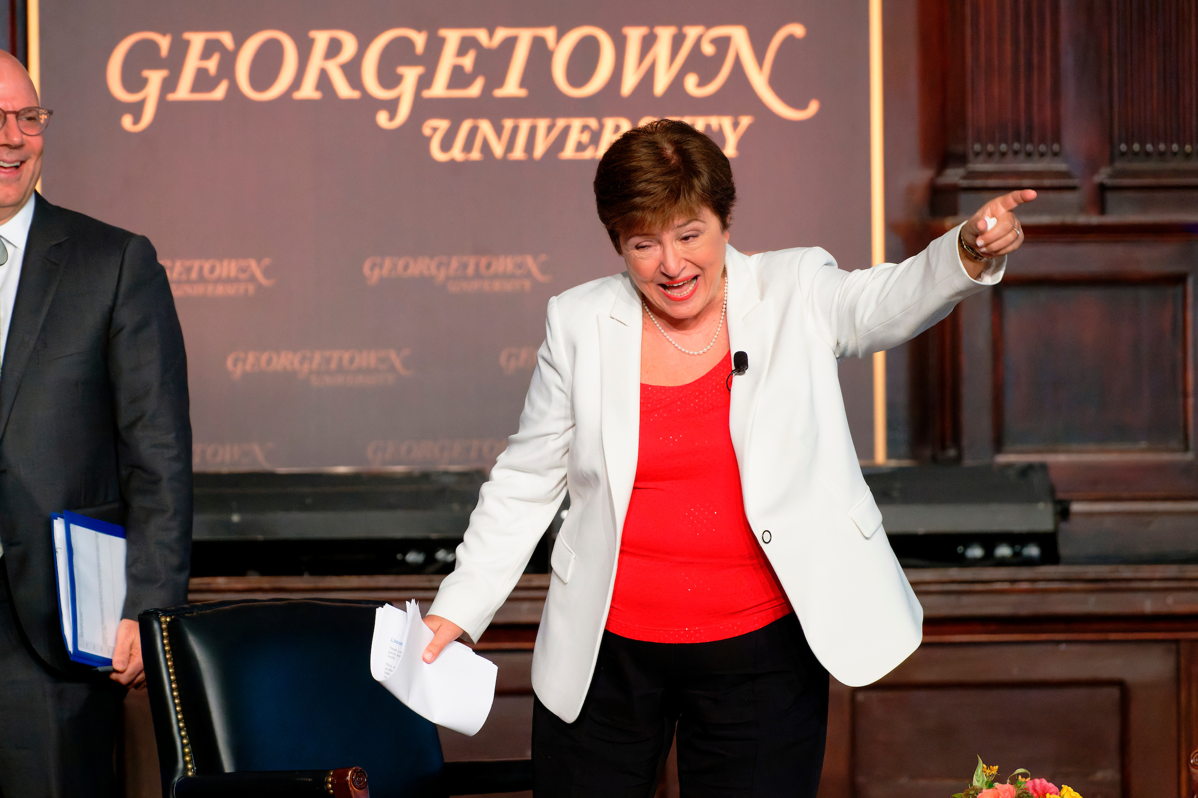 Kristalina Georgieva wears a red blouse and white blazer and points out to the audience while smiling